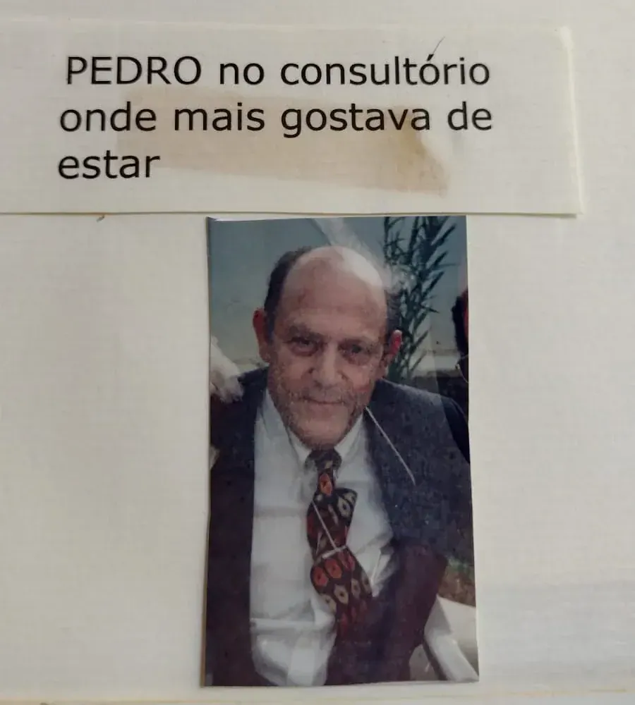 Foto de Pedro de terno e gravata estampada colada em uma página com a legenda "Pedro no consultório onde mais gostava de estar"
